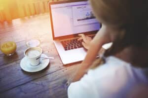 femme travaillant sur son ordinateur en buvant son cafe